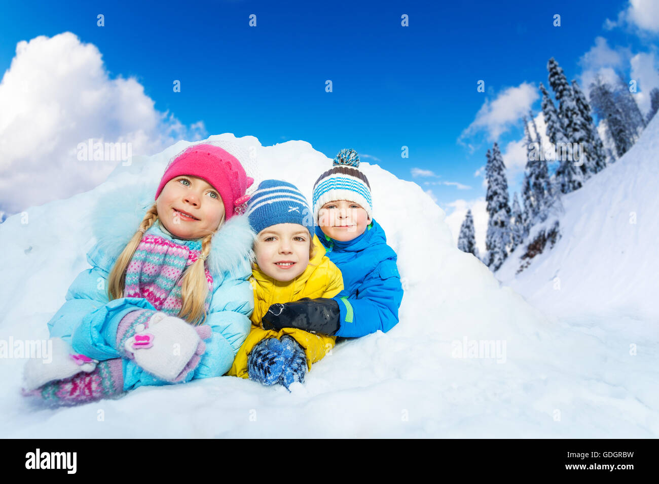 Trois petits enfants sourire à partir de la caverne de neige Banque D'Images