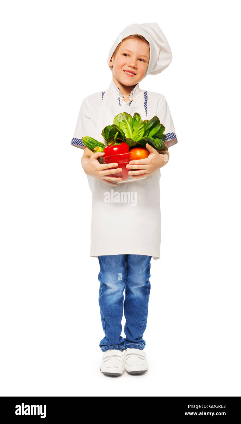 Garçon dans l'uniforme de cook holding bowl avec des légumes Banque D'Images