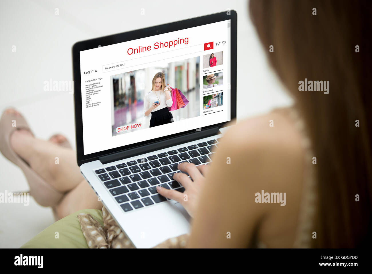 Jeune femme shopper shopping en ligne sur le site de l'habillement à l'aide d'ordinateur portable. Modèle de mode Caucasian woman sitting on sofa Banque D'Images