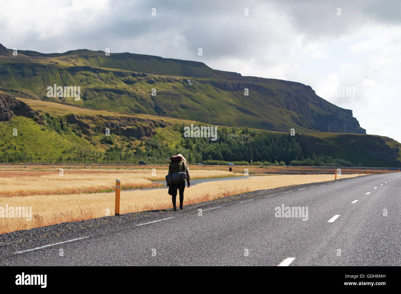 L'Islande, l'Europe : une fille qui marche sur la Route 1, le célèbre Ring Road qui fait le tour de l'île, dans le domaine de la cascade de Seljalandsfoss Banque D'Images