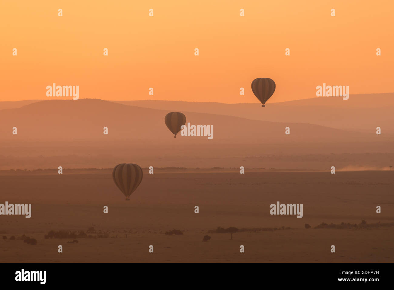 Trois montgolfières survoler les collines basses de la savane africaine. La perspective aérienne rend les collines semblent différentes sha Banque D'Images