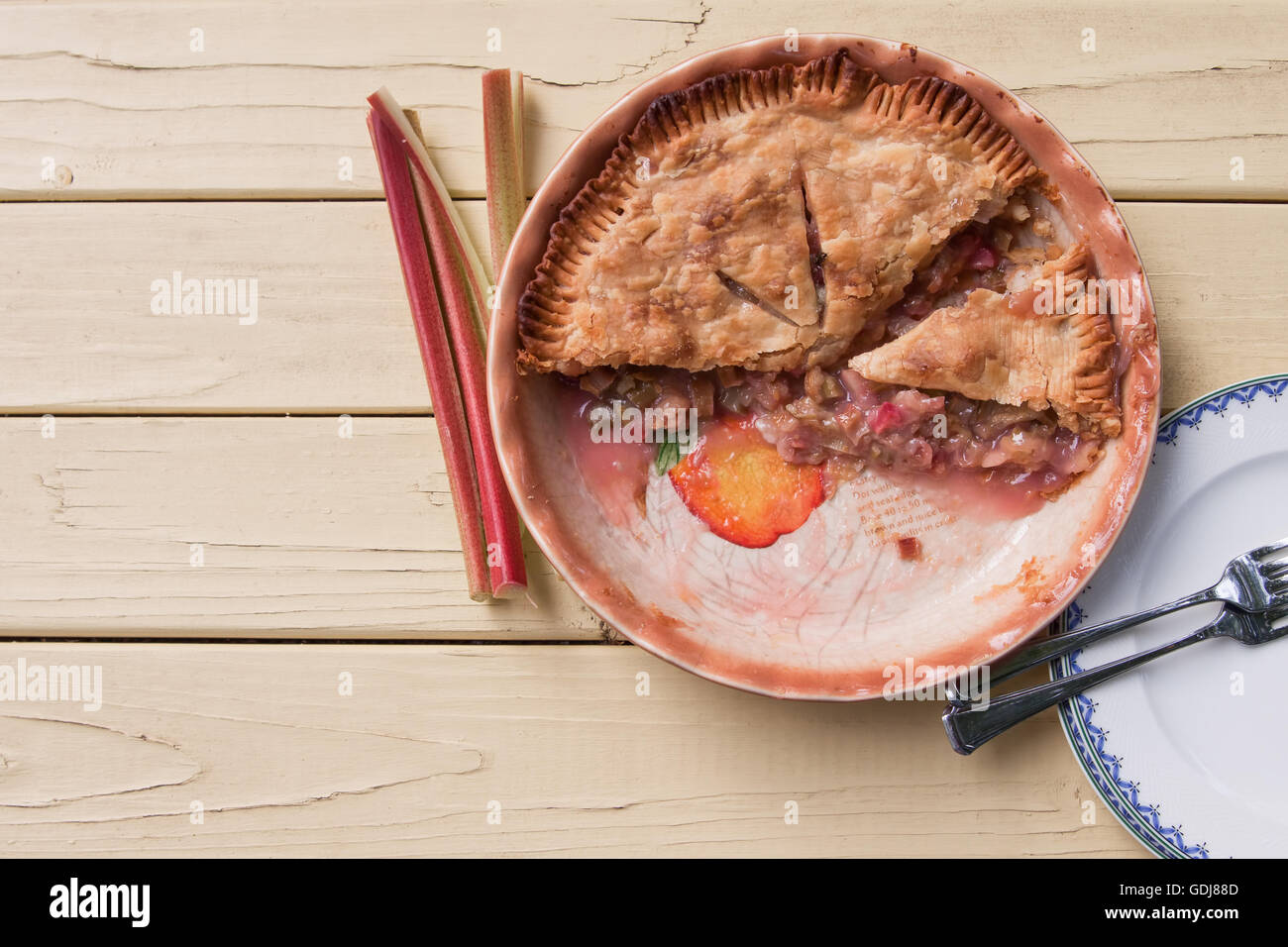 Tarte à la rhubarbe fraîchement cuit, tranché et prêt à servir sur table jaune - Vue de dessus Banque D'Images
