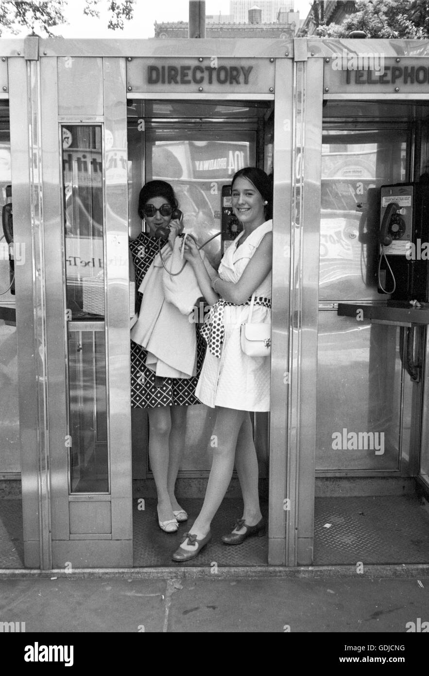 Deux femmes profitez de l'intimité d'une cabine téléphonique dans le centre de Manhattan en 1969. Banque D'Images
