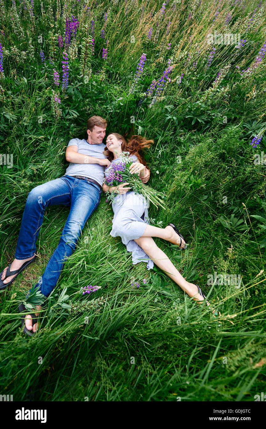 Couple in love allongé dans l'herbe sur une prairie d'été Banque D'Images