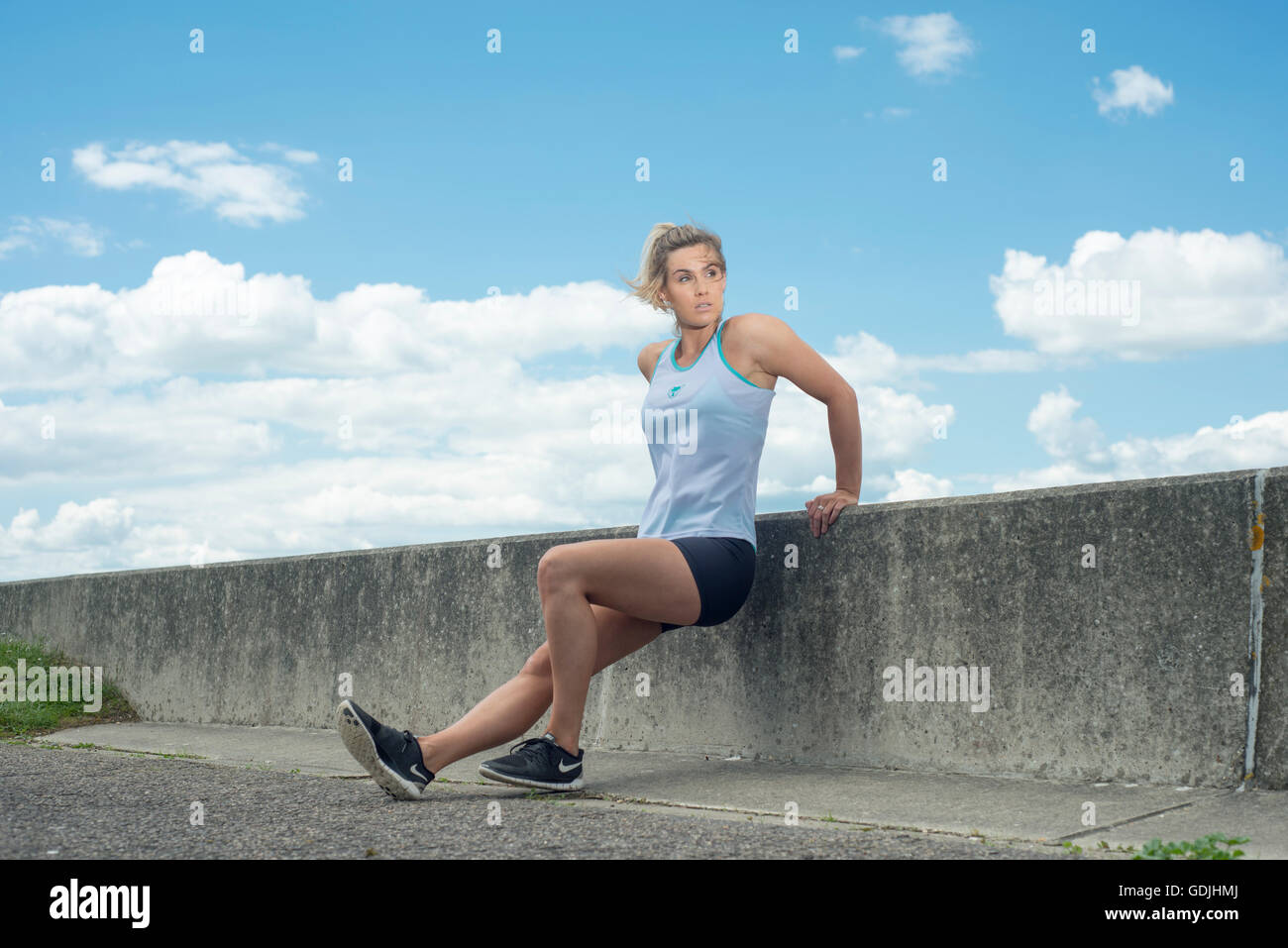 Fit woman faisant retour press ups contre un mur Banque D'Images