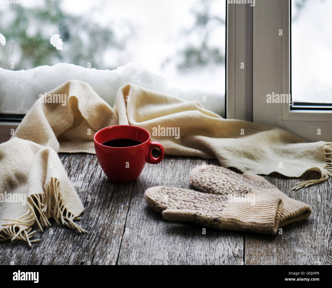 La tasse de café ou de thé, beige écharpe et mitaines de womans sont situés sur le rebord en bois stylisés. Un concept de confort d'hiver Banque D'Images