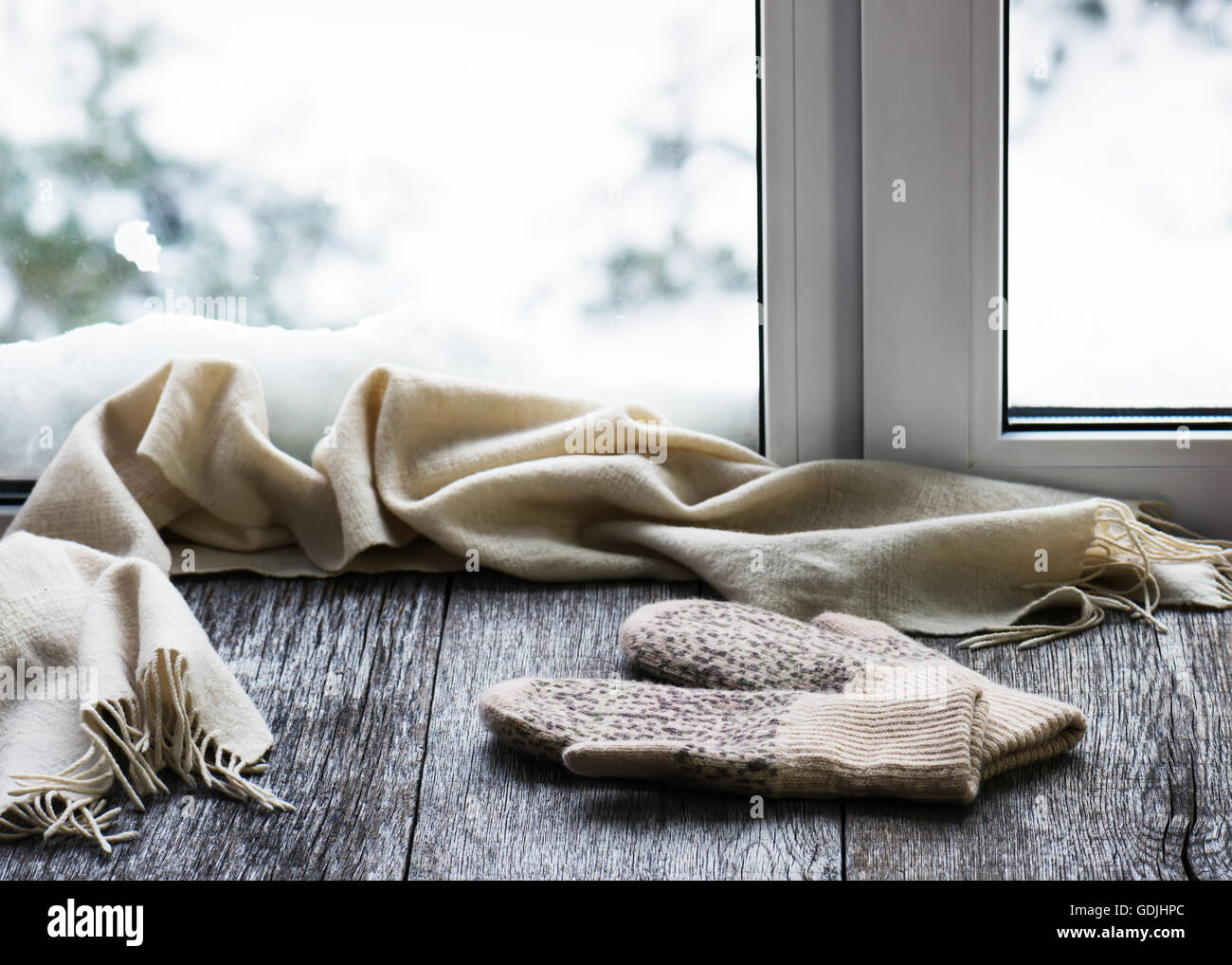 Écharpe et mitaines en laine beige situé sur un rebord de fenêtre en bois stylisés. Winter concept de confort et de détente. Banque D'Images