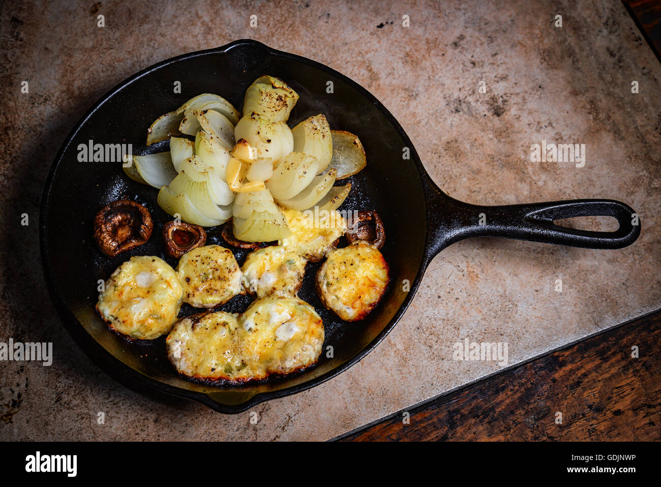 Les champignons farcis et l'oignon dans une poêle en fonte Banque D'Images