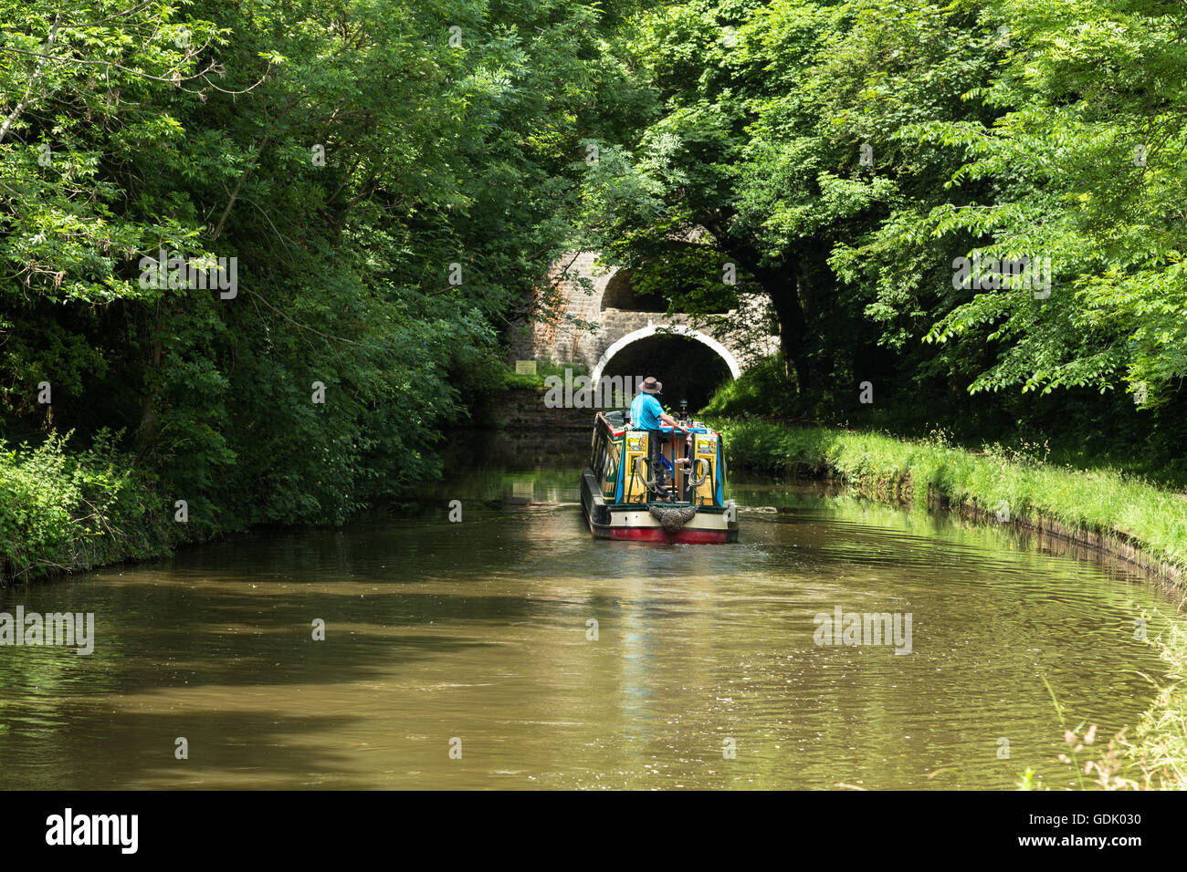 Homme avec un chapeau pilote un bateau sur le canal conduit à Liverpool canal au Moyen-Orient Marton, Yorkshire Banque D'Images