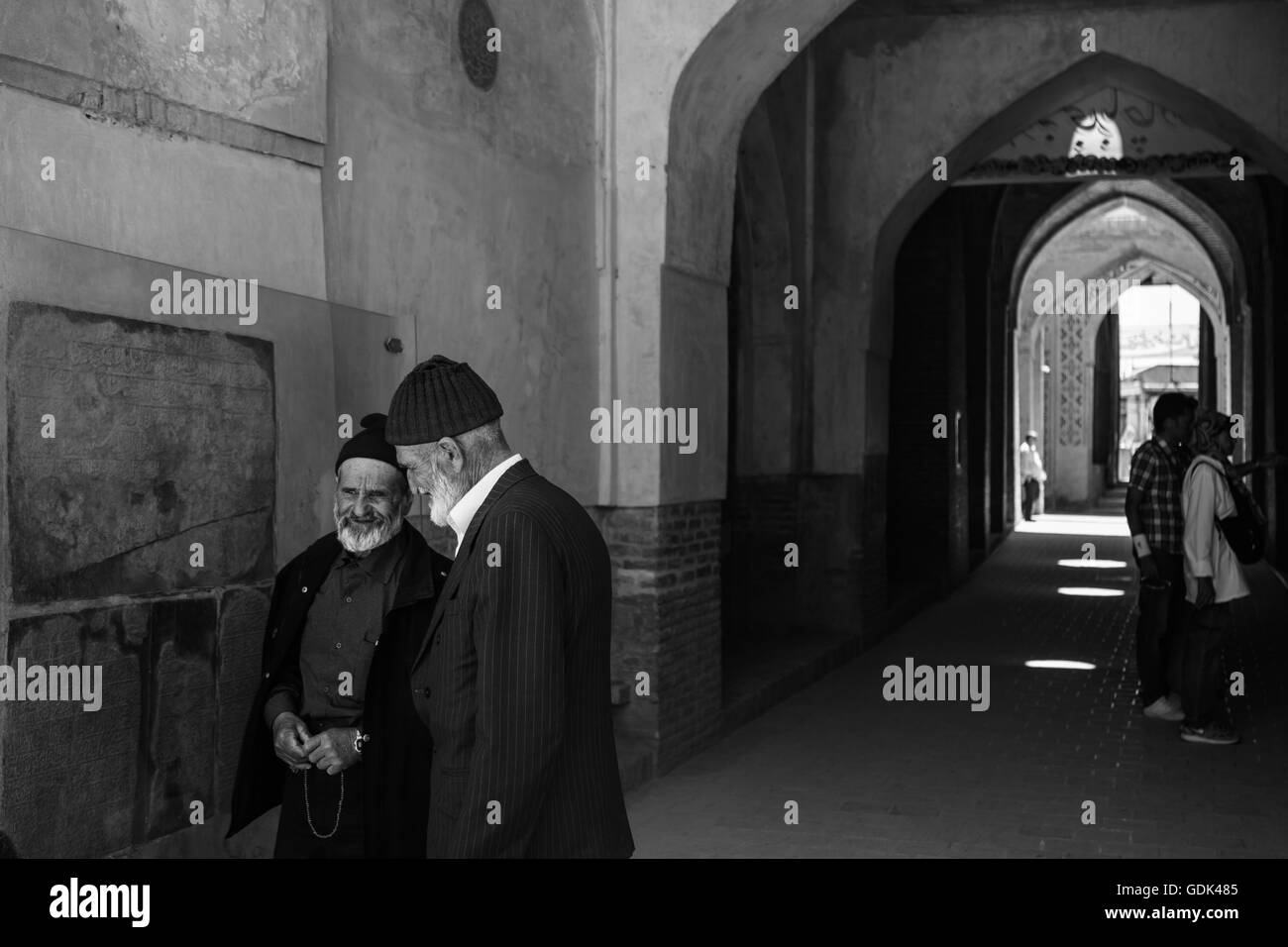 Deux vieux hommes, venus pour la prière, sont à la recherche d'un mur à la gravure et à se parler dans la mosquée Jame à Isfahan Banque D'Images