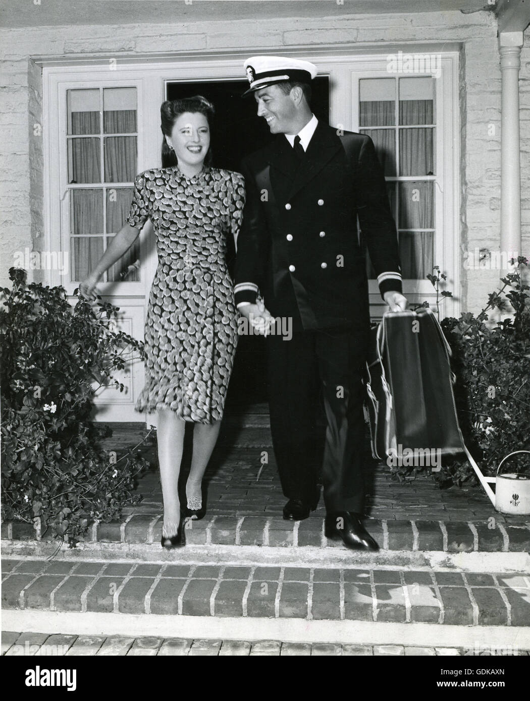Épouse Barbara Stanwyck promenades avec le Lieutenant Robert Taylor pour la voiture comme l'écran star quitte la Marine active de service. Banque D'Images