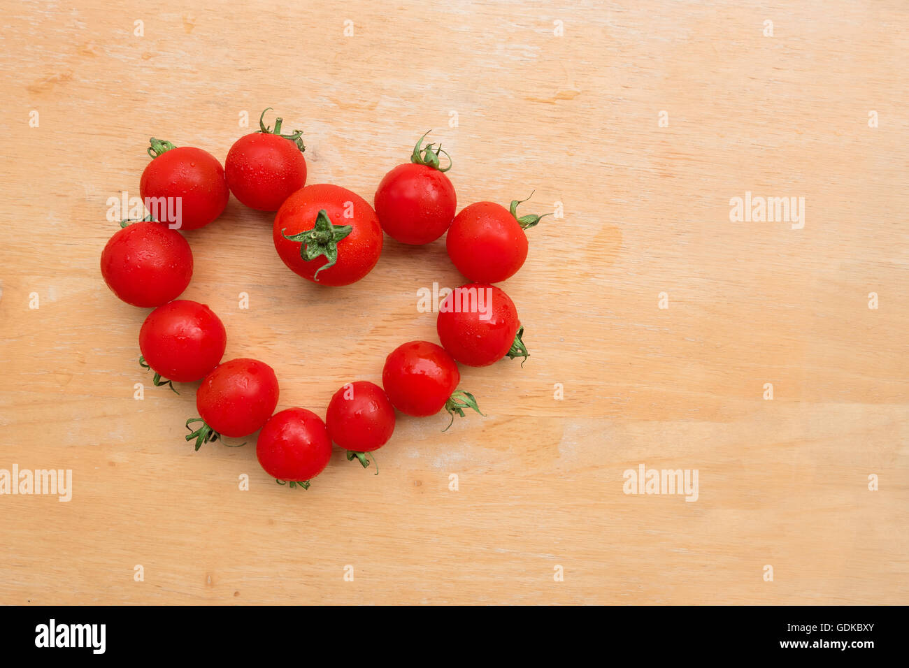 Frais de tomates cerises en forme de coeur sur la planche à découper en bois, télévision lay Banque D'Images