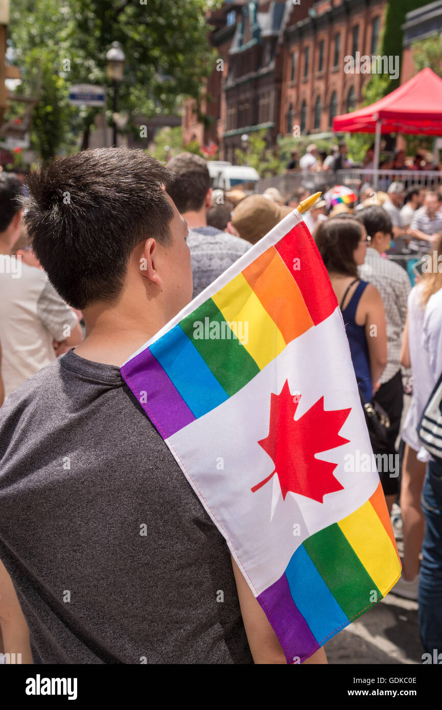 Toronto, Canada - le 3 juillet 2016 : Un spectateur mâle est à regarder la parade de la gay pride, tenant un drapeau arc-en-ciel Canada gay Banque D'Images