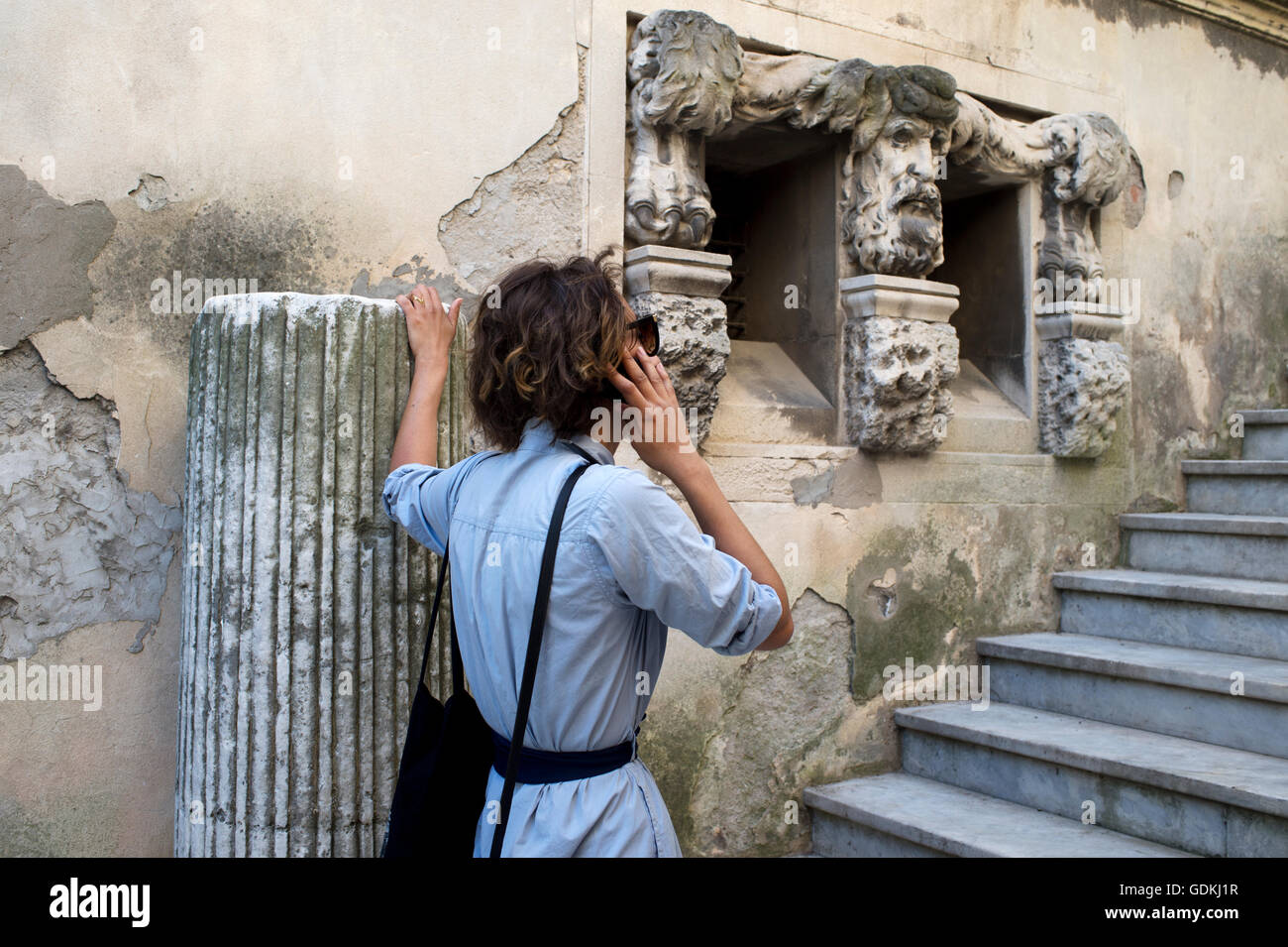 La France. Arles. Une jeune femme parle sur un téléphone portable à côté de certains vestiges romains Banque D'Images
