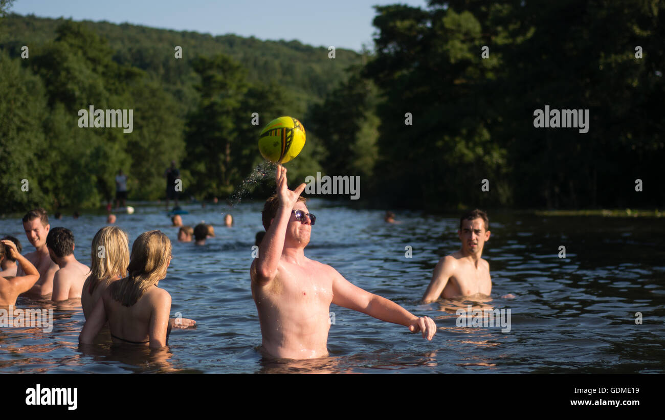 Man throwing ball dans la rivière Avon, avec les nageurs. Des centaines affluent à Warleigh Weir 3 miles de baignoire sur la journée la plus chaude de l'année Banque D'Images