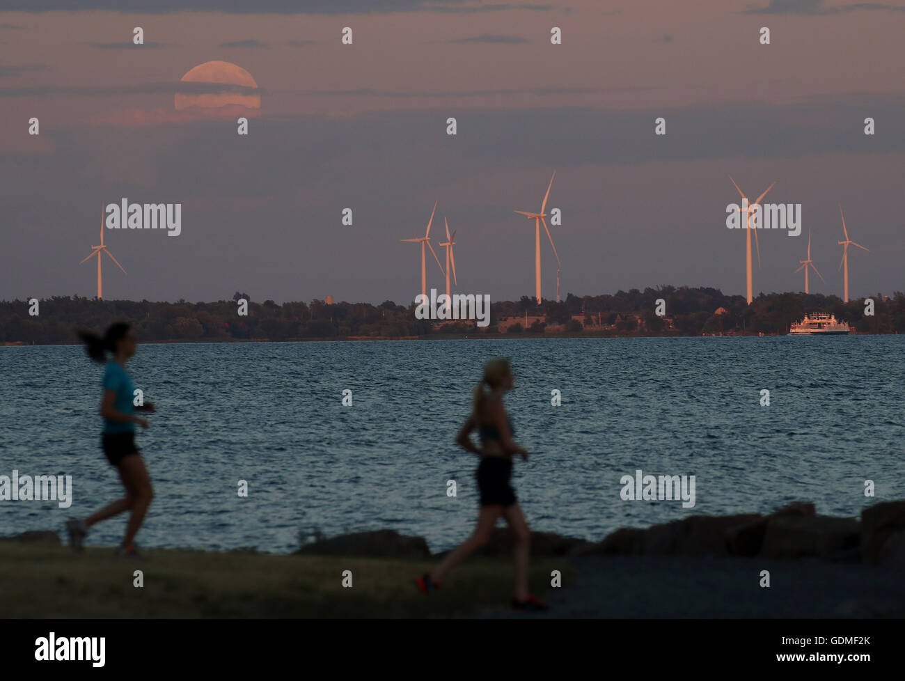 Kingston, Ontario, Canada. 19 juillet, 2016. Rebecca Argent, Sarah Muma et Elena Jean faire l'exercice que la pleine lune se lève au-dessus du lac Ontario à Kingston (Ontario), le 19 juillet 2016. Credit : Lars Hagberg/ZUMA/Alamy Fil Live News Banque D'Images