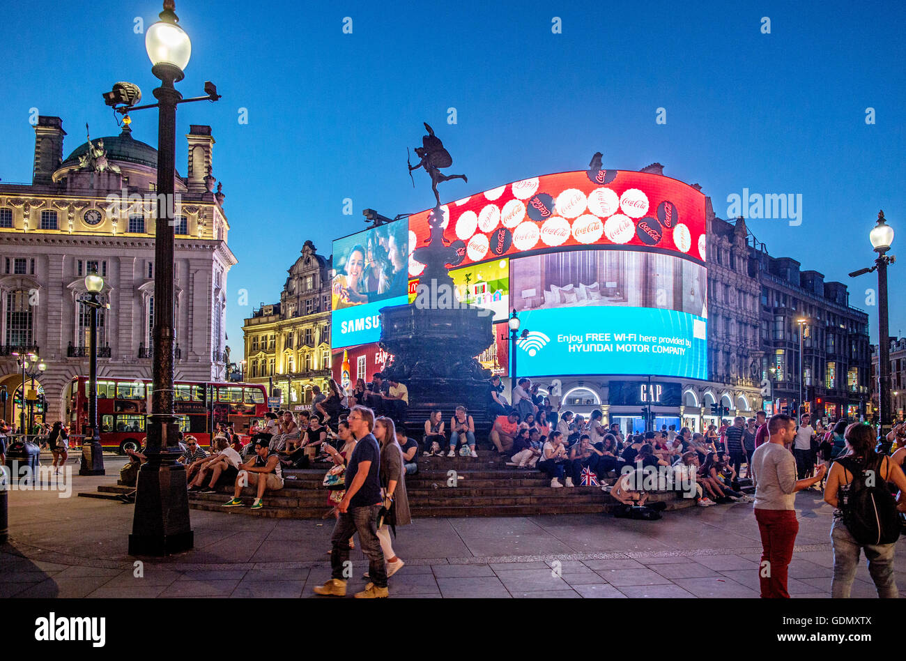 Les gens assis autour de l'Eros Monument Piccadilly Circus London UK Banque D'Images