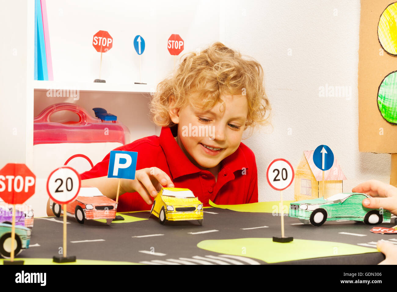 Cute boy playing with toy conducteur voitures papier Banque D'Images