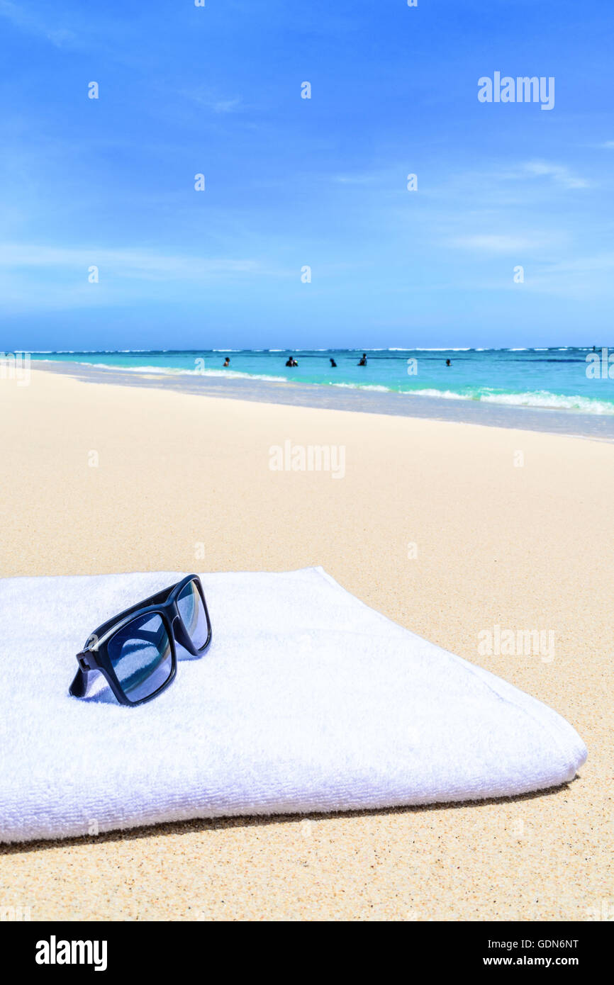 Lunettes de soleil et serviette blanche sur une belle plage tropicale Banque D'Images