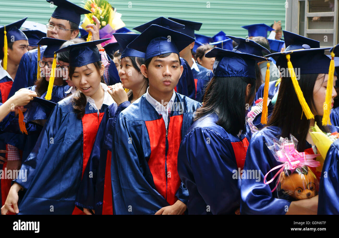 Groupe de jeunes élèves en uniforme, tenir debout robe bouquet, sourire sur diplôme cérémonie à l'université Banque D'Images