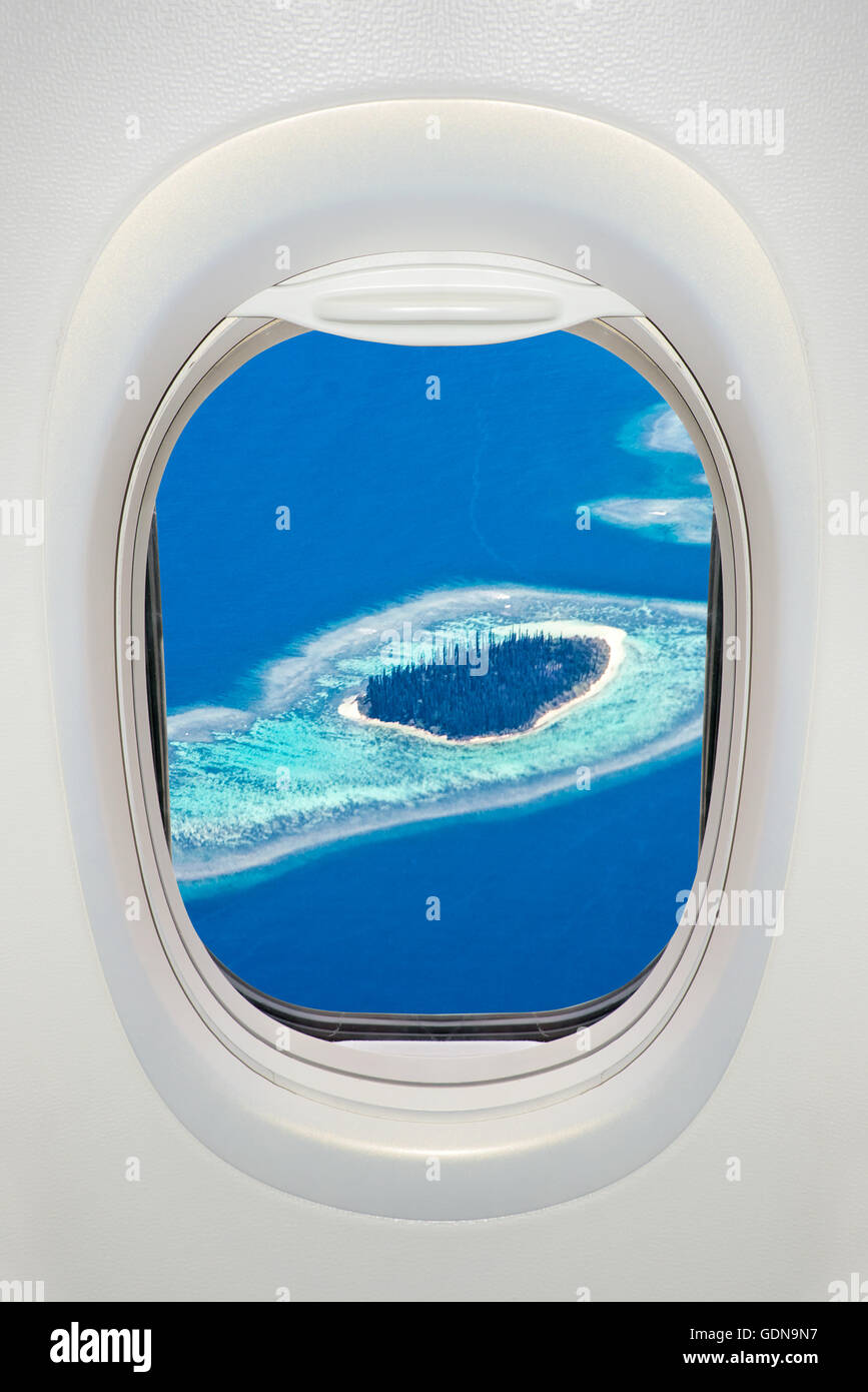 Fenêtre d'un avion de l'intérieur, vue sur une île tropicale Banque D'Images
