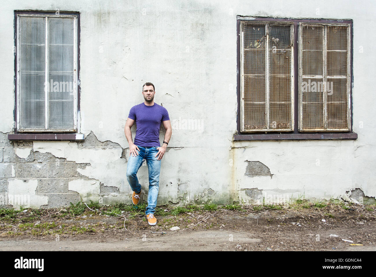Beau jeune homme est debout sur le mur de la rue Banque D'Images