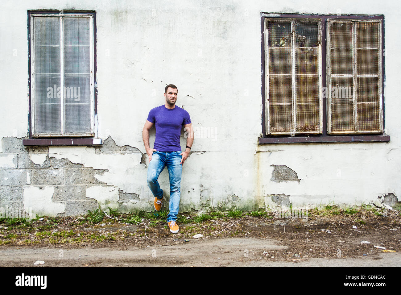 Beau jeune homme est debout sur le mur de la rue Banque D'Images