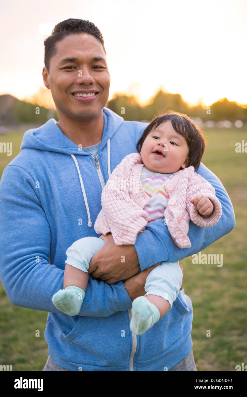 Père berçant bébé dans park Banque D'Images