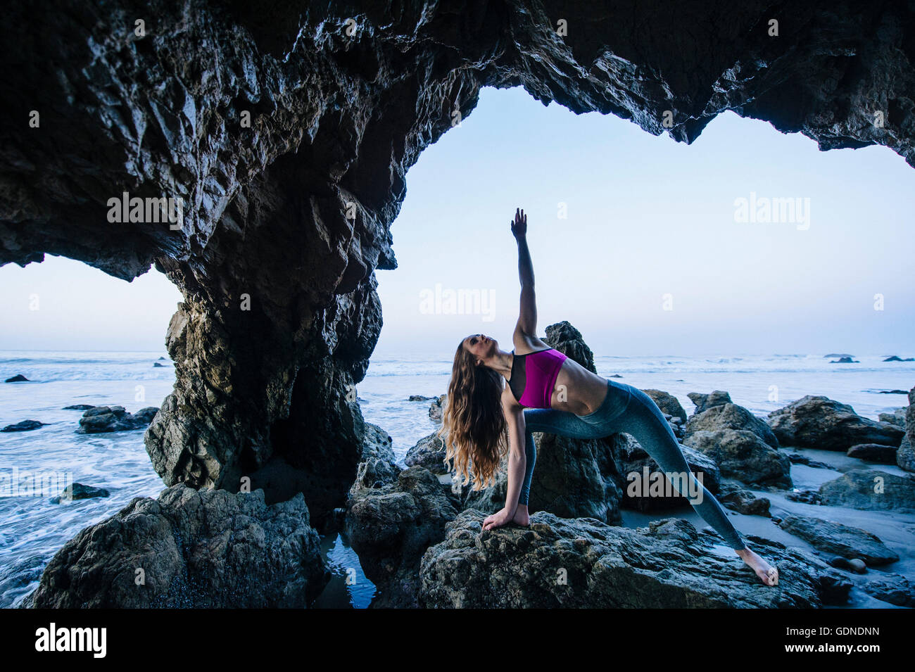 Jeune danseuse en équilibre en équilibre sur la main dans la grotte de la mer, Los Angeles, Californie, USA Banque D'Images