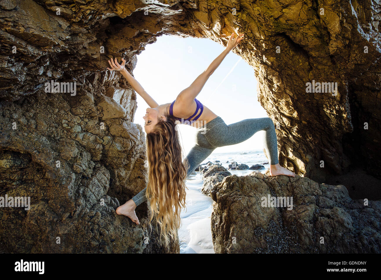Jeune danseuse en équilibre dans la grotte de la mer de jeter ses longs cheveux en arrière, Los Angeles, Californie, USA Banque D'Images