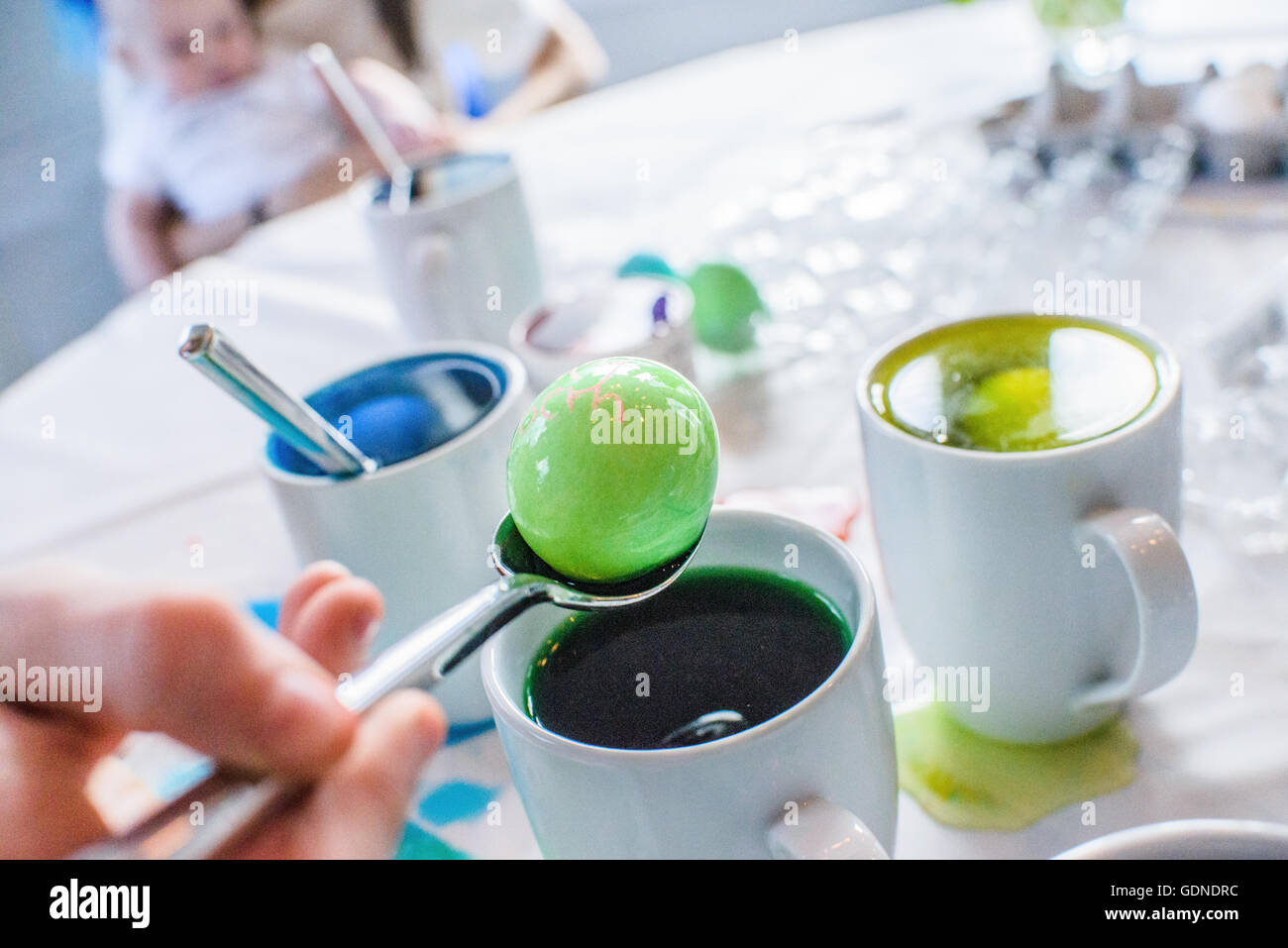 Close up of main dépose des oeufs teints vert à partir de mug sur la table pour Pâques Banque D'Images