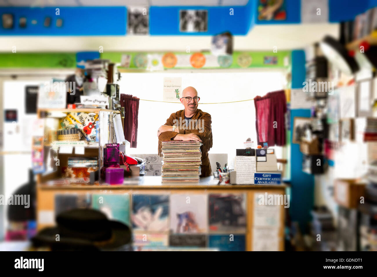 Portrait of mature man in record shop, leaning on stack d'enregistrements Banque D'Images