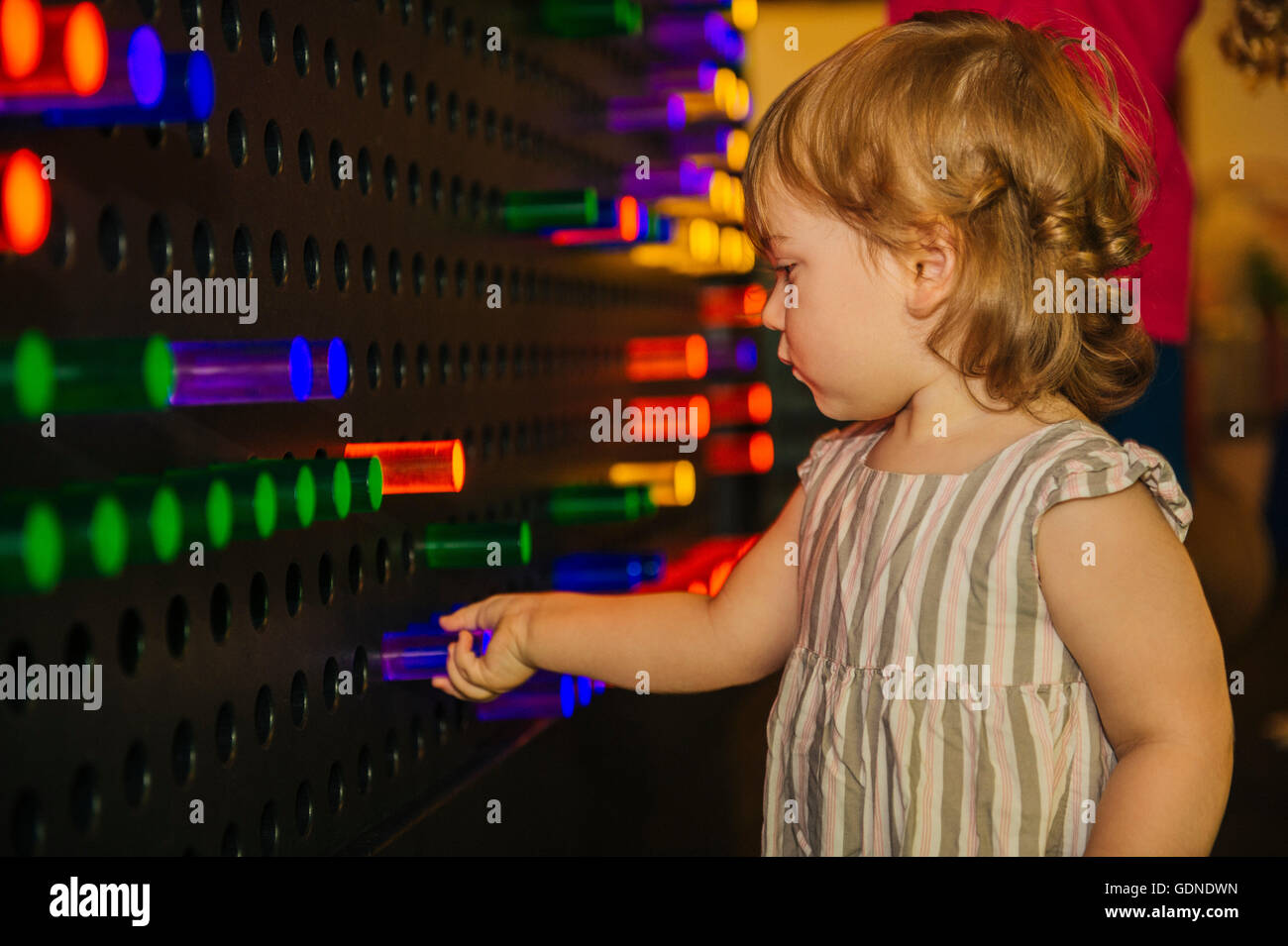 Female toddler jouant avec panneau lumineux colorés Banque D'Images