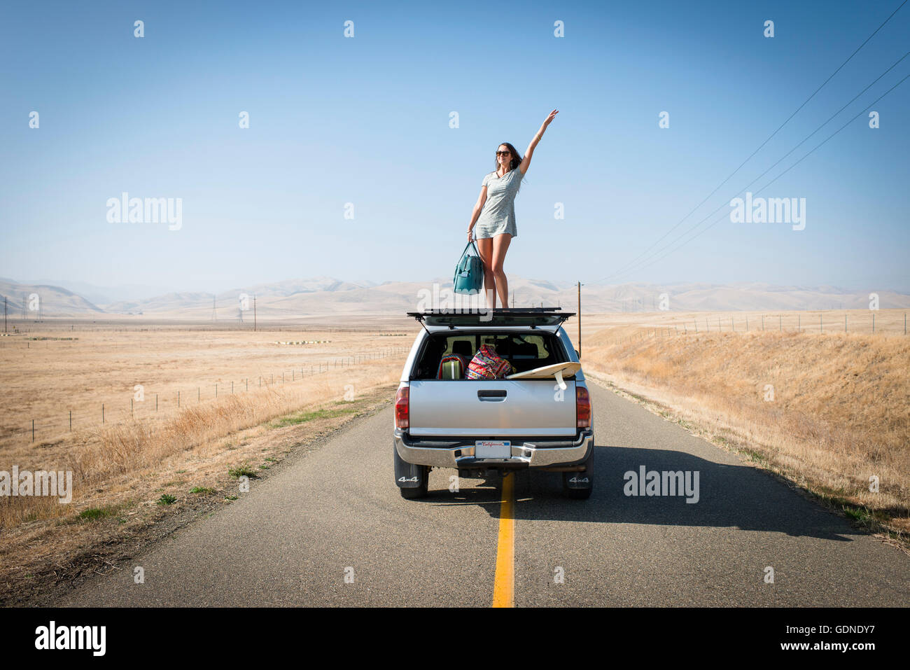 Femme debout sur toit de voiture, l'autoroute 1, California, USA Banque D'Images