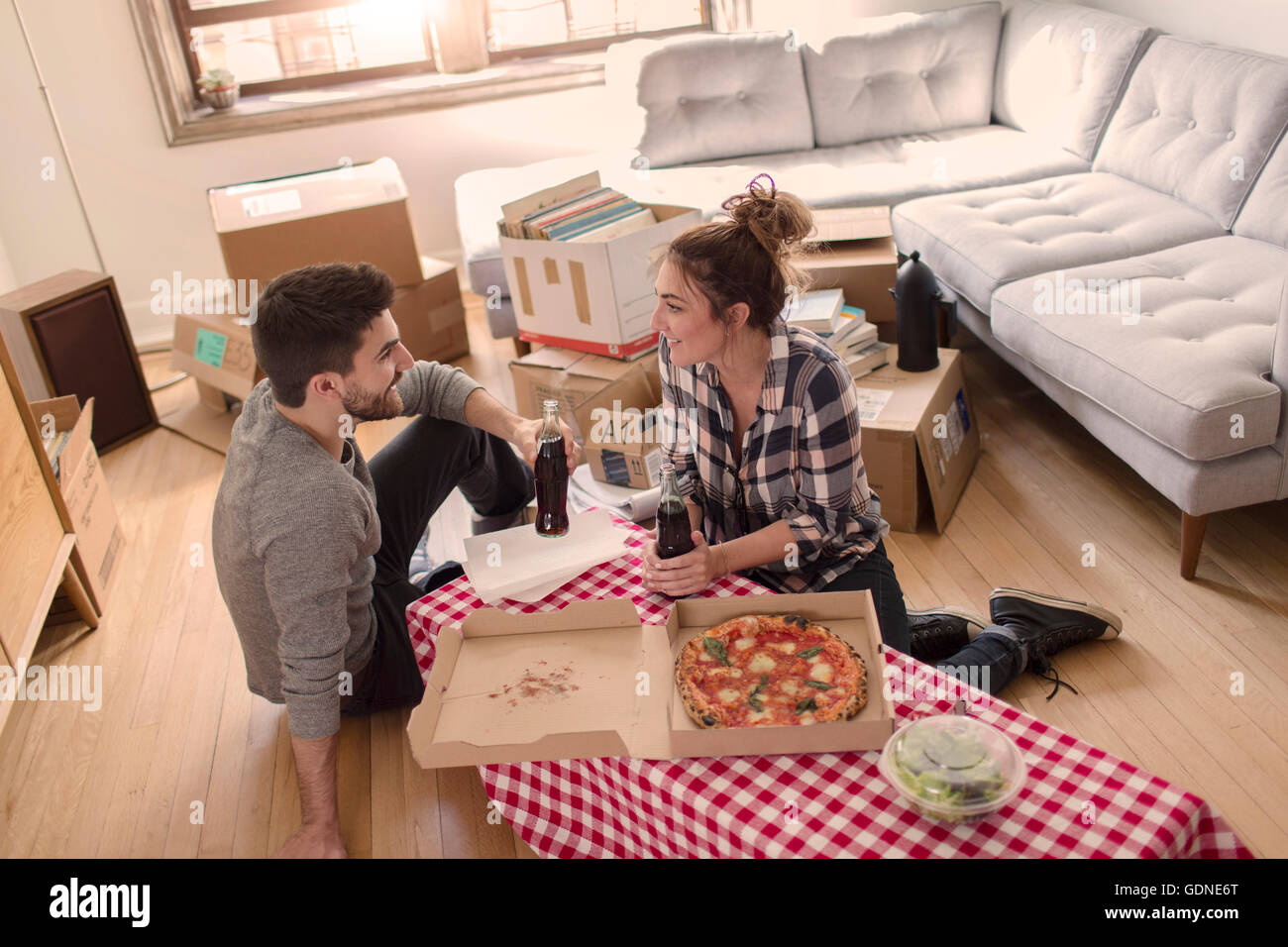 Déménagement : manger une pizza dans la nouvelle maison, entouré par des zones Banque D'Images