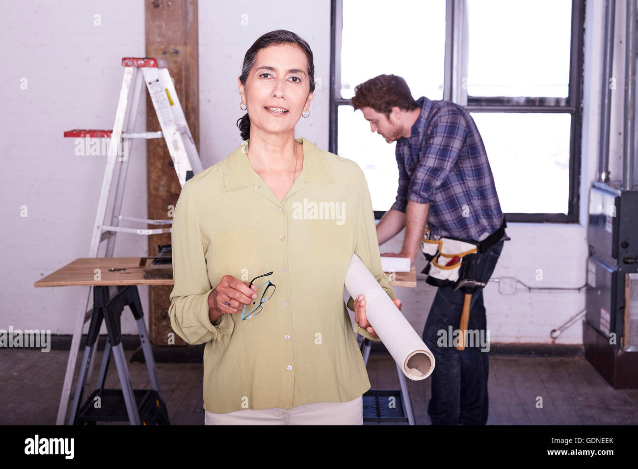 Woman holding blueprint smiling at camera Banque D'Images
