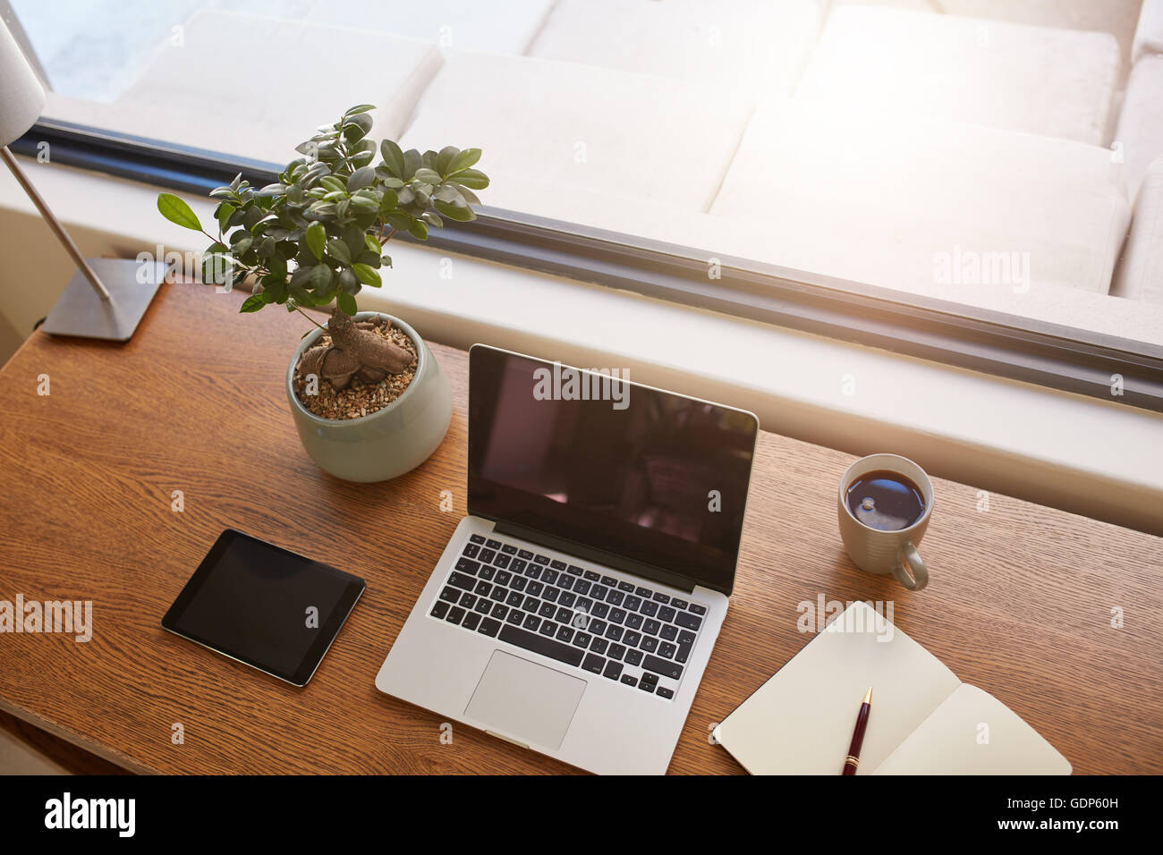 Vue supérieure de la tourné d'ordinateur portable, tablette numérique, plante en pot, un journal et une tasse de café sur la table en bois. Bureau moderne par un Banque D'Images