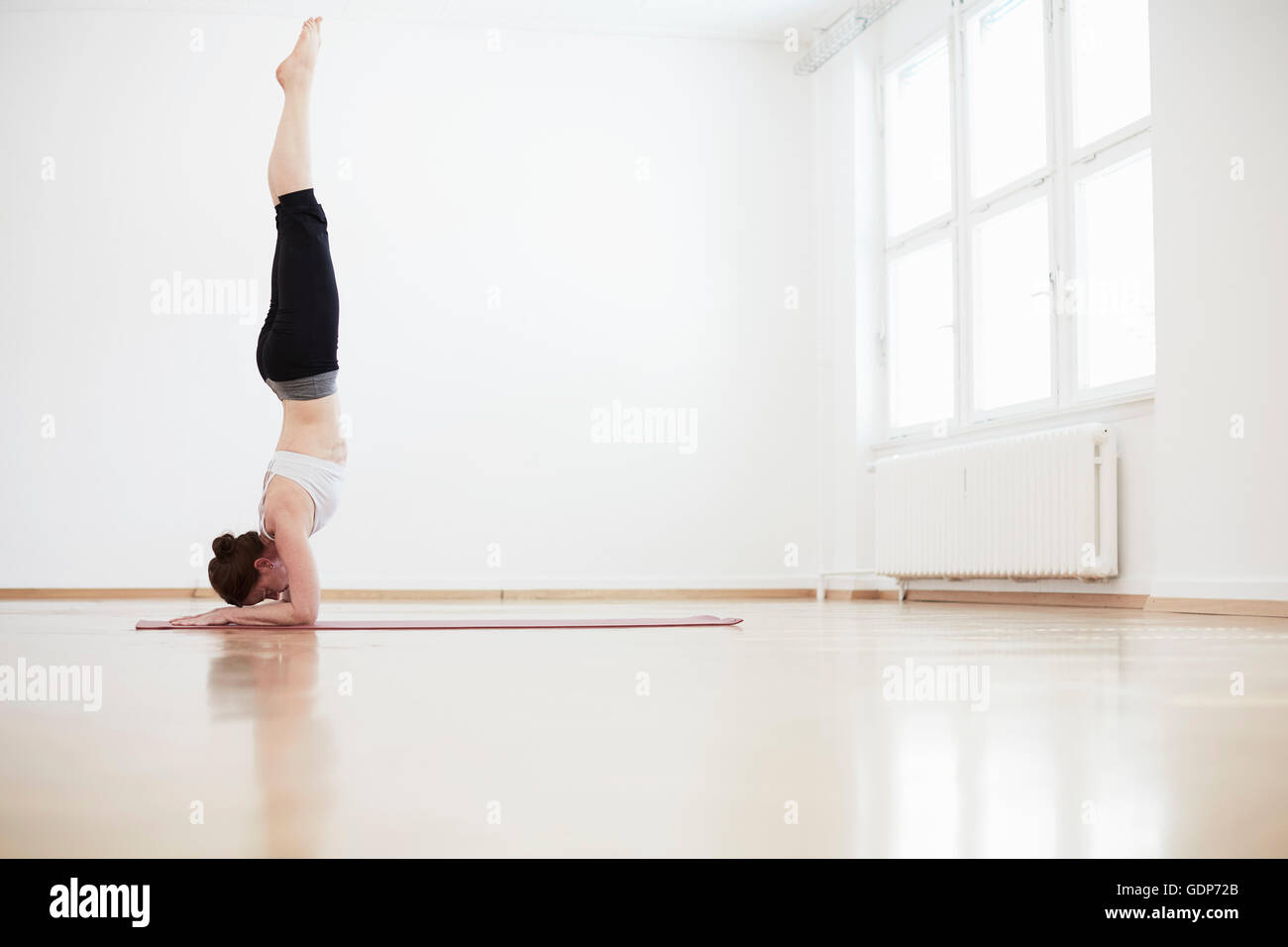 Side view of woman in studio exercice doing handstand Banque D'Images