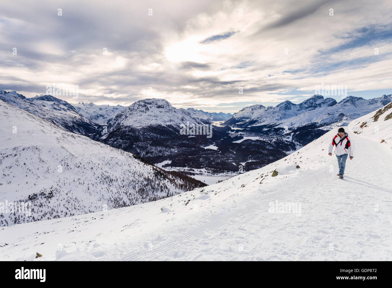 Homme marchant sur la montagne couverte de neige, vue arrière, Engadine, Suisse Banque D'Images