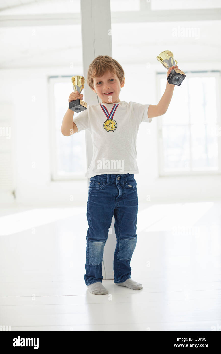 Portrait of boy holding up trophées et médaille d'or de l'usure Banque D'Images