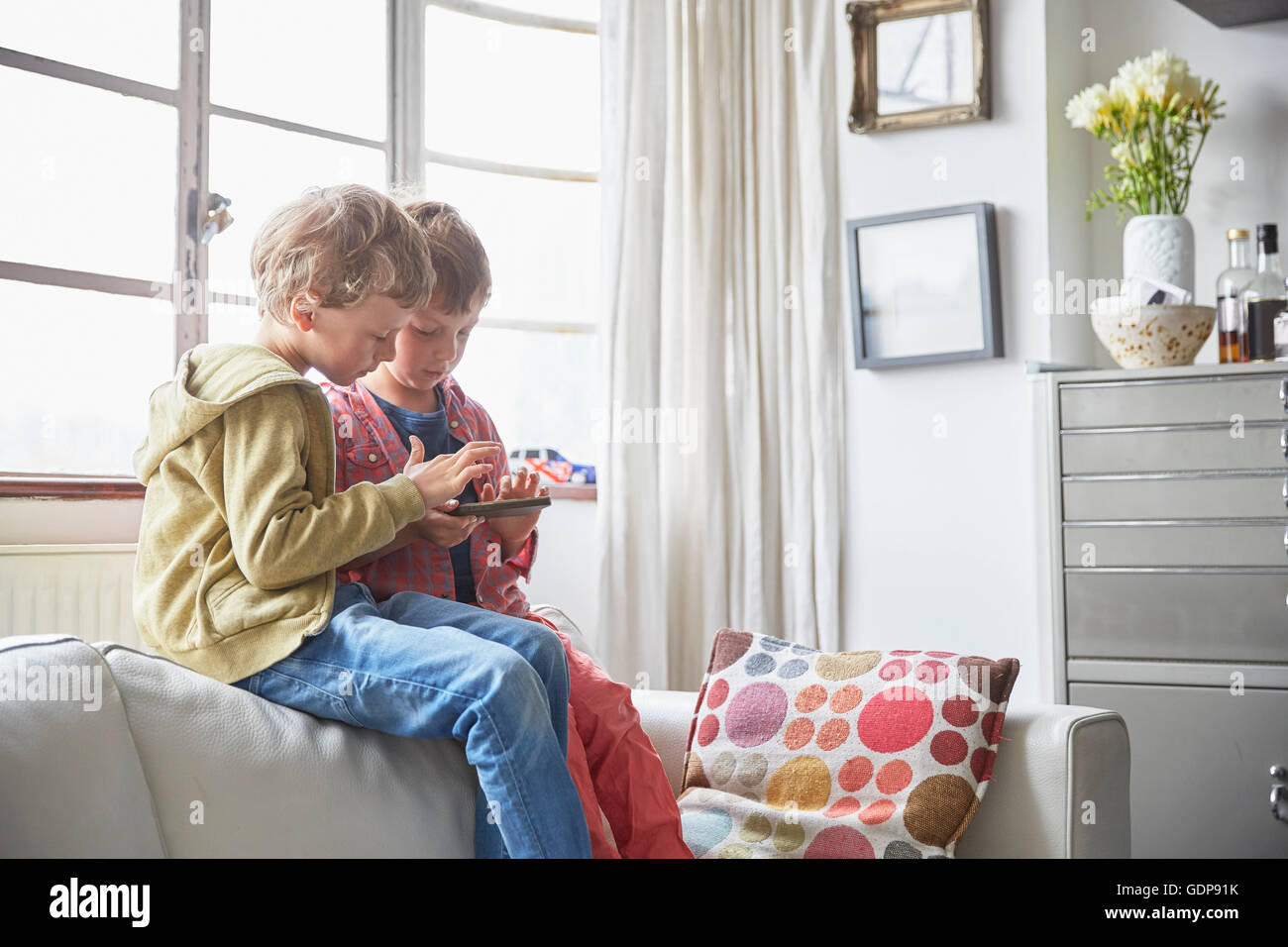 Garçons assis sur le canapé looking at smartphone Banque D'Images