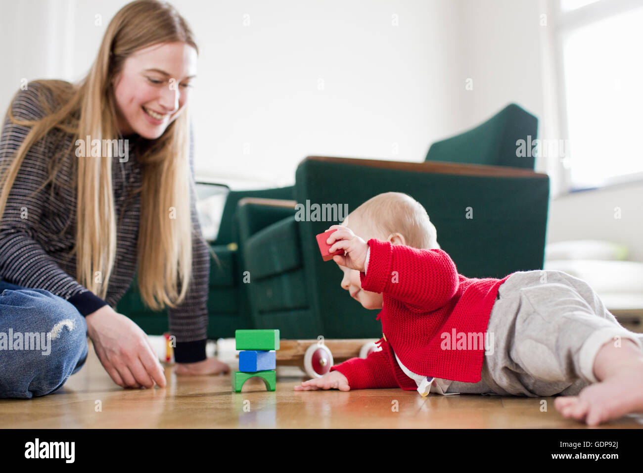 Femme et fille de bébé jouer avec des éléments de base sur plancher du salon Banque D'Images