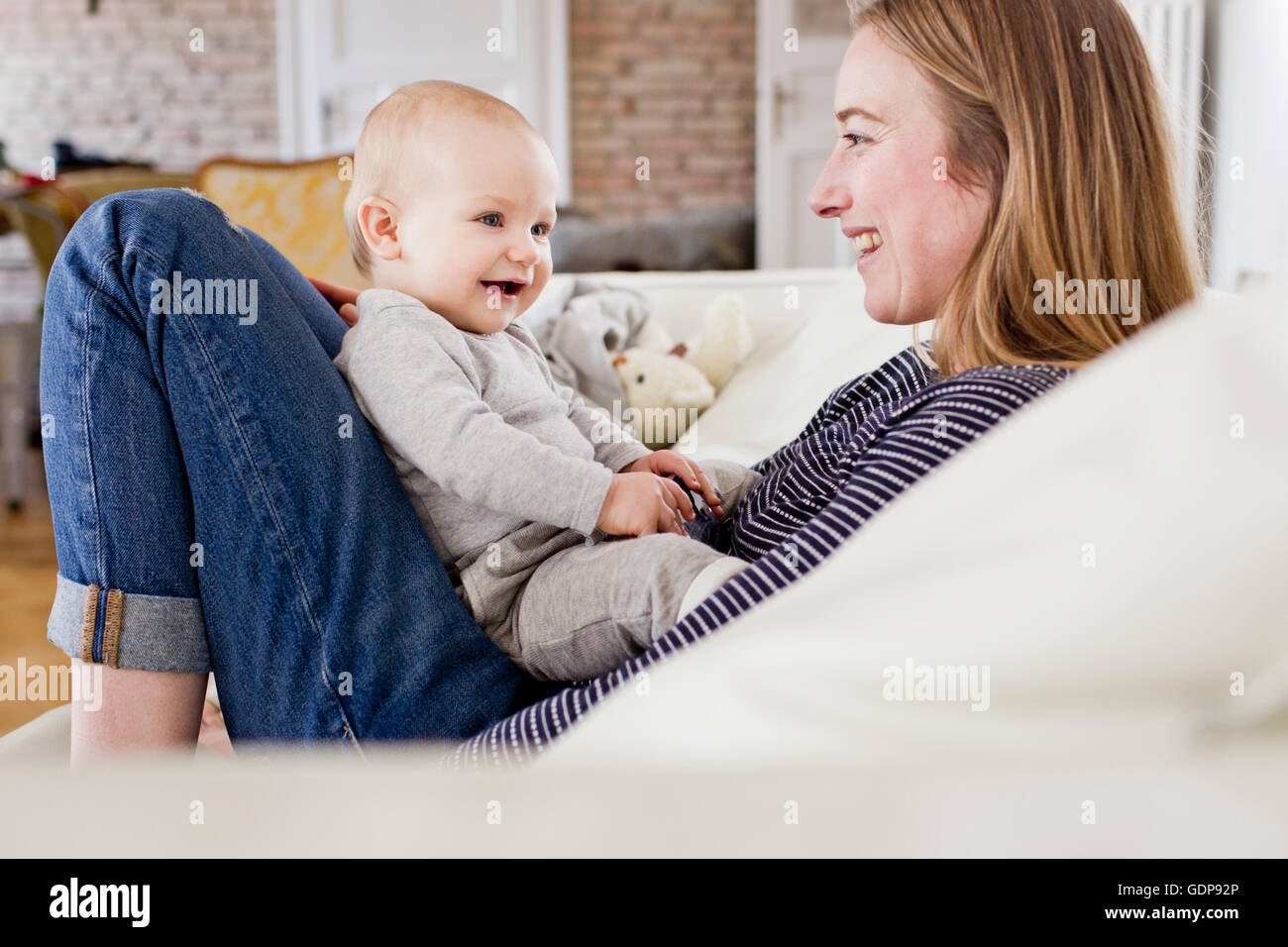 Mère et fille bébé face à face sur le canapé Banque D'Images