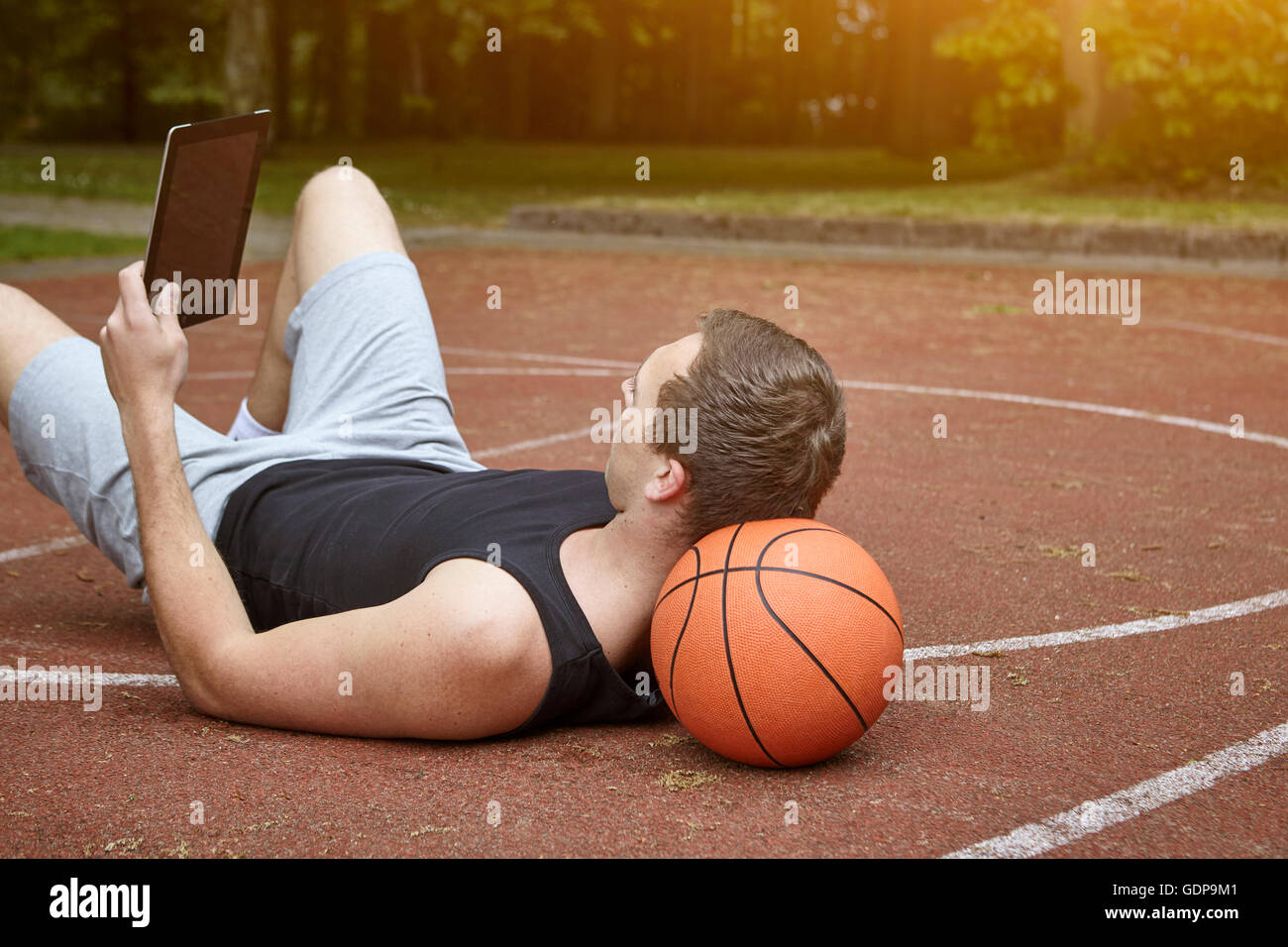 Jeune joueur de basket-ball masculin allongé sur tablette numérique  navigation sur cour Photo Stock - Alamy