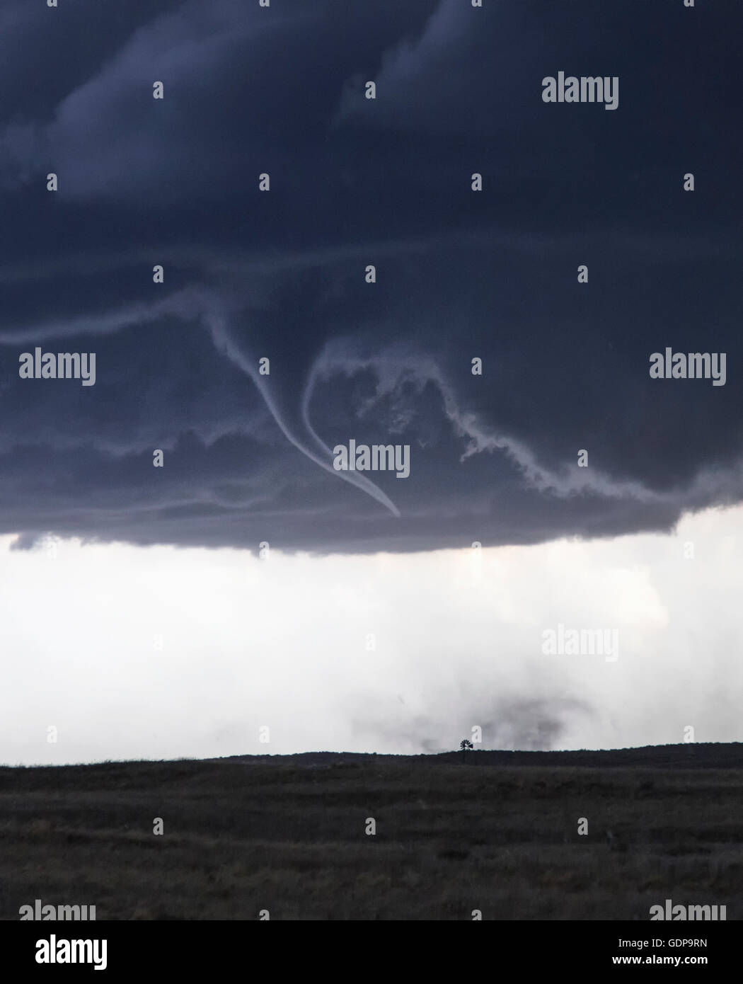 Tornado avec entonnoir nuageux sur paysage de champ Banque D'Images