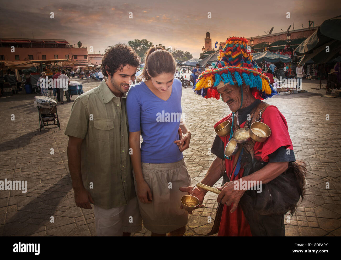 Jeune couple de discuter avec l'opérateur de marché, la place Jemaa el-Fnaa, Marrakech, Maroc Banque D'Images
