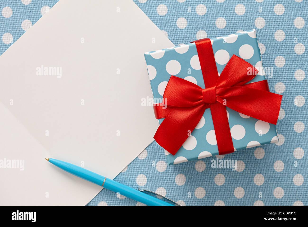 Boîte cadeau à pois bleu, stylo et carte de souhaits Banque D'Images