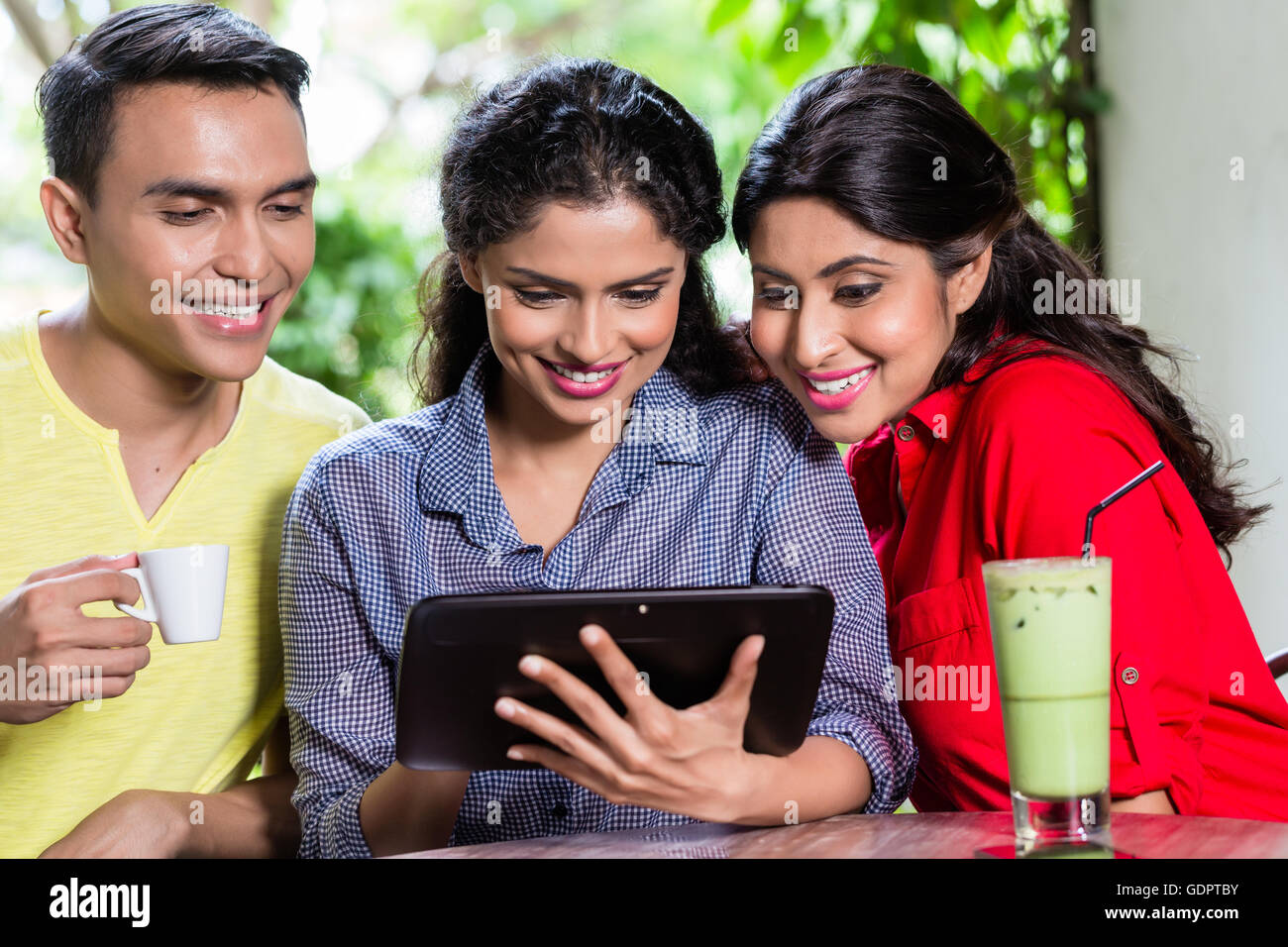 Groupe de jeunes Indiens à la tablette à l'ordinateur tout en étant assis dans le café Banque D'Images