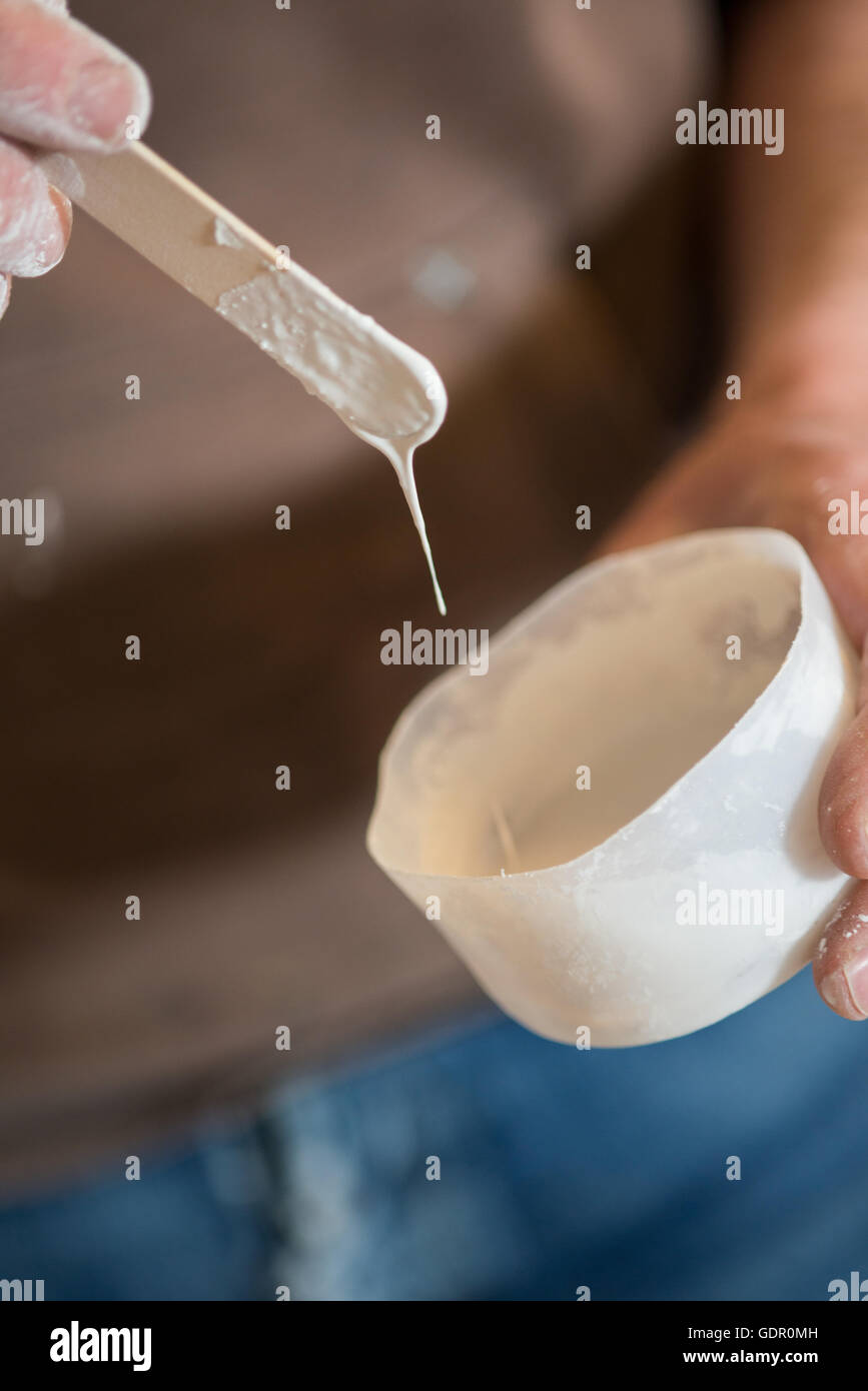 Une petite quantité de peinture blanche étant mélangé avec un bâtonnet de bois Banque D'Images