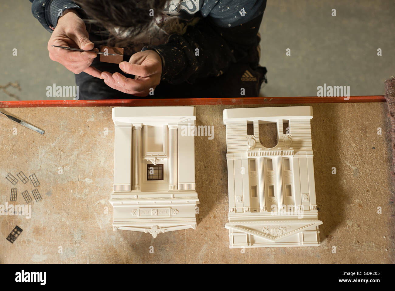 Vue de dessus d'un homme plaçant soigneusement toute petite sur windows à l'échelle des bâtiments modèle en plâtre Banque D'Images